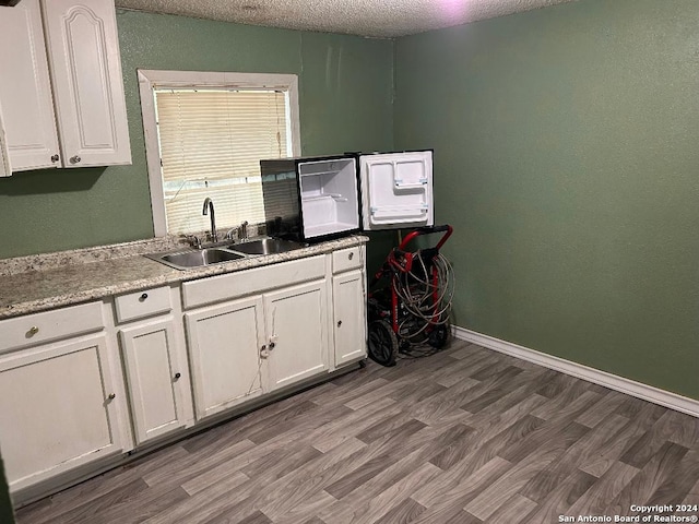 kitchen with sink, white cabinets, a textured ceiling, and hardwood / wood-style flooring