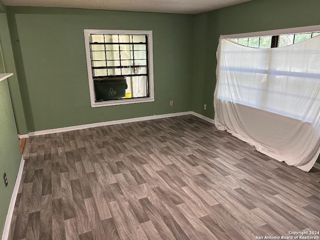 unfurnished room with a healthy amount of sunlight, hardwood / wood-style floors, and a textured ceiling