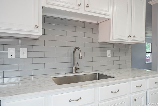 kitchen featuring white cabinets, light stone countertops, sink, and tasteful backsplash