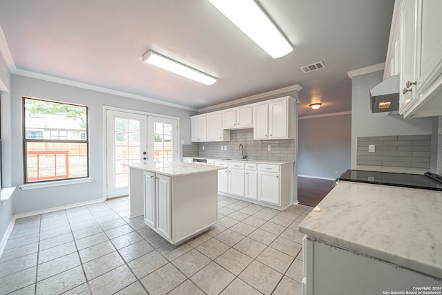 kitchen featuring white cabinets, a center island, sink, and backsplash