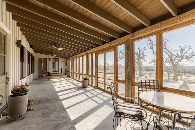 sunroom with plenty of natural light, ceiling fan, wooden ceiling, and lofted ceiling with beams