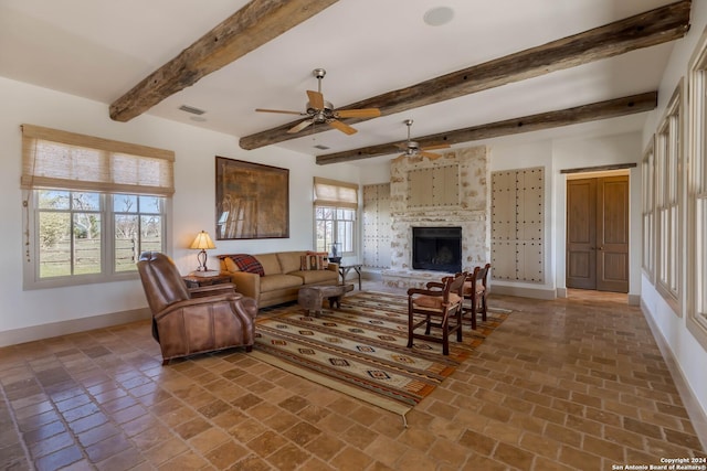 living room featuring beamed ceiling, ceiling fan, and a large fireplace