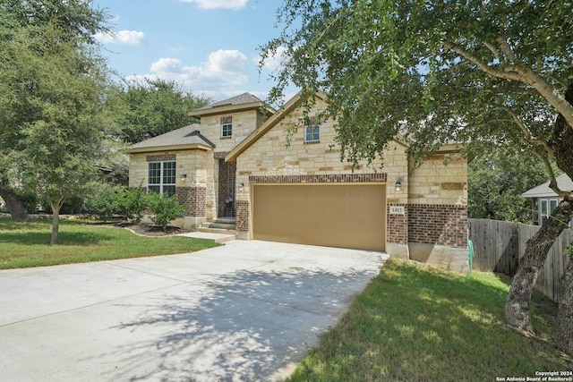 view of front of home with driveway, stone siding, fence, a front yard, and an attached garage