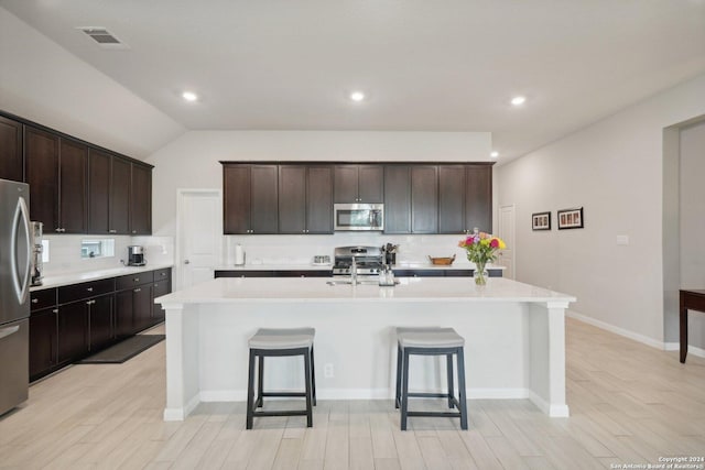 kitchen with stainless steel appliances, a kitchen breakfast bar, decorative backsplash, and light countertops