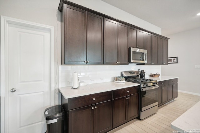 kitchen with dark brown cabinetry, light wood-style flooring, stainless steel appliances, and light countertops