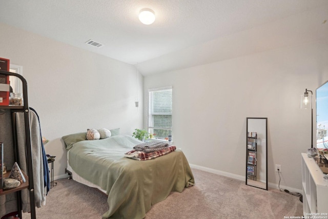 bedroom featuring visible vents, light carpet, a textured ceiling, baseboards, and vaulted ceiling