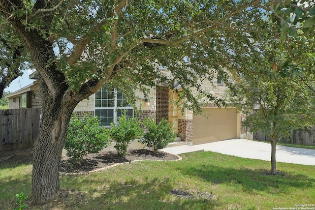 obstructed view of property with fence, concrete driveway, a front yard, a garage, and brick siding