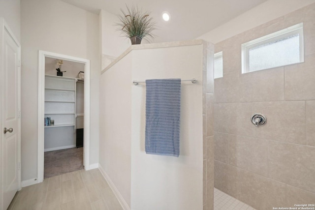 bathroom with a spacious closet, baseboards, and walk in shower