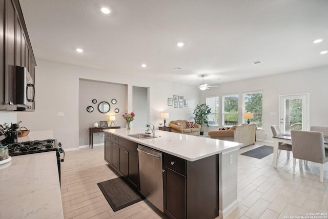 kitchen with recessed lighting, a sink, stainless steel appliances, dark brown cabinetry, and open floor plan