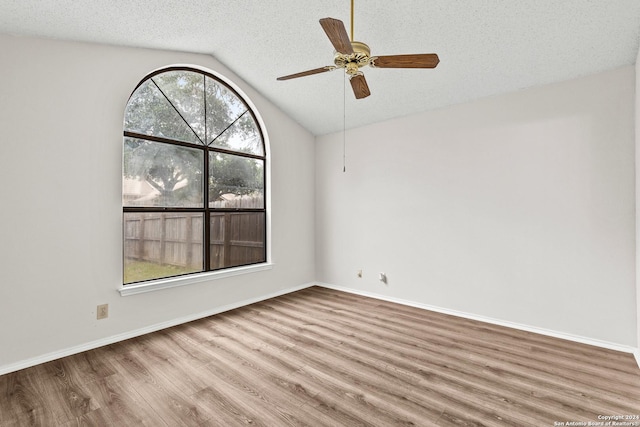 empty room featuring wood-type flooring, a textured ceiling, and lofted ceiling