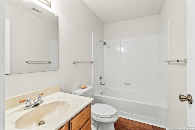 full bathroom with hardwood / wood-style floors, a textured ceiling, toilet, vanity, and tiled shower / bath