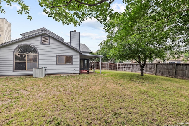 rear view of house with cooling unit and a yard