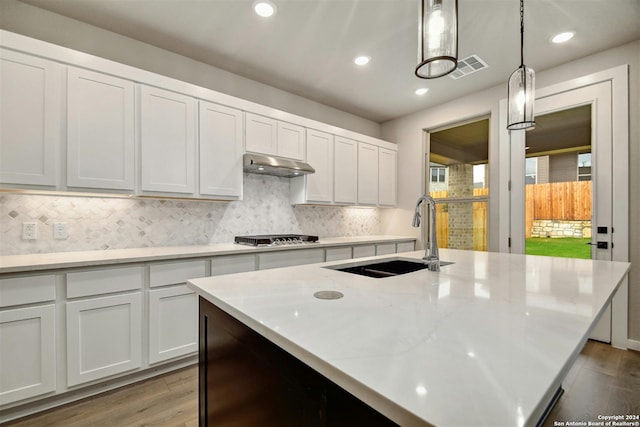 kitchen with extractor fan, sink, pendant lighting, wood-type flooring, and white cabinets