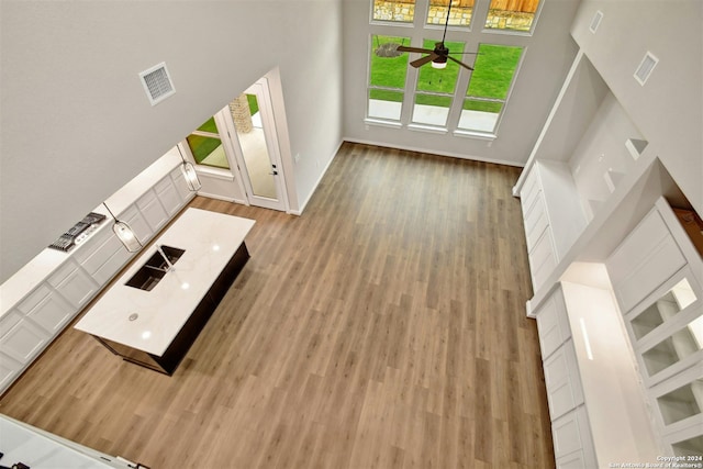 unfurnished living room with plenty of natural light, wood-type flooring, sink, and a high ceiling