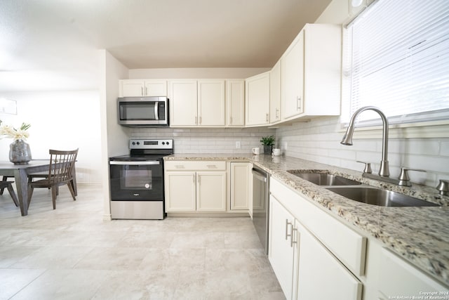 kitchen with sink, light stone counters, decorative backsplash, white cabinets, and appliances with stainless steel finishes