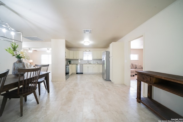 kitchen with backsplash, sink, ceiling fan, white cabinetry, and stainless steel appliances