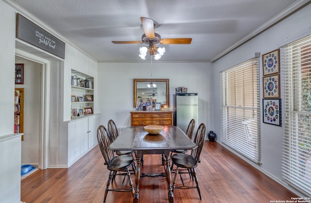 dining area with a textured ceiling, ceiling fan, crown molding, built in features, and hardwood / wood-style floors