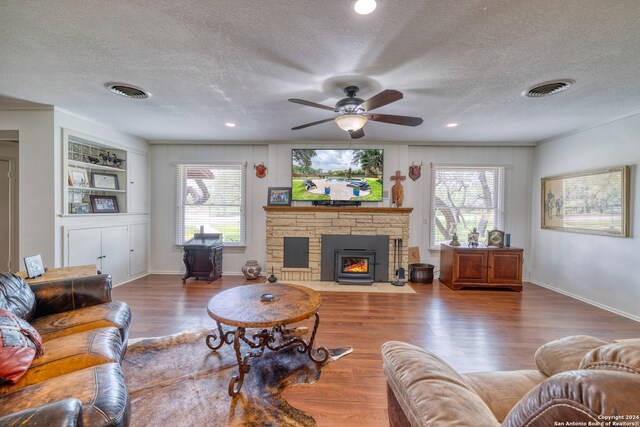 living room featuring wood-type flooring, a textured ceiling, a wealth of natural light, and ceiling fan