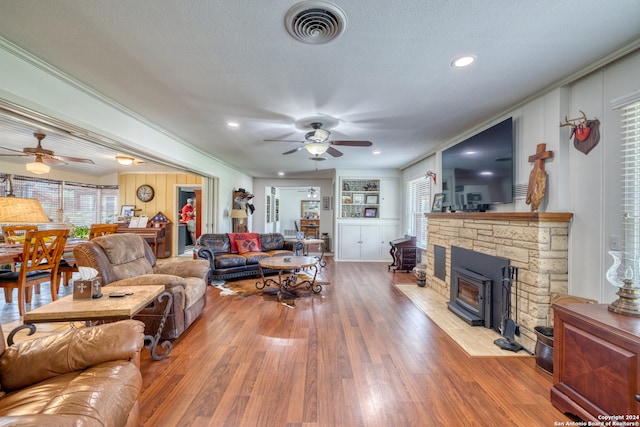 living room with hardwood / wood-style floors, a wood stove, and ceiling fan