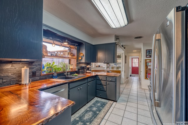 kitchen featuring butcher block countertops, backsplash, stainless steel appliances, and a textured ceiling