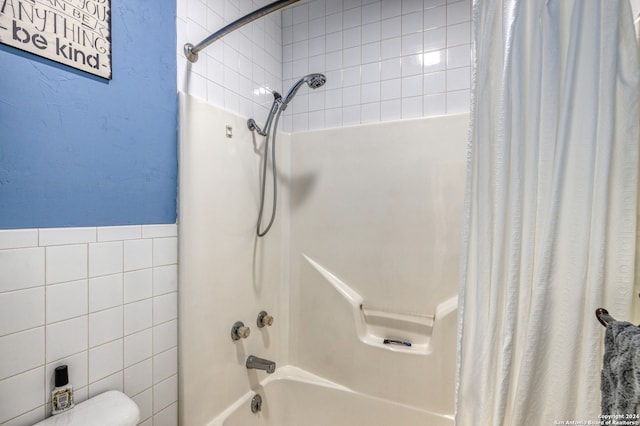 bathroom featuring shower / bathtub combination with curtain and tile walls