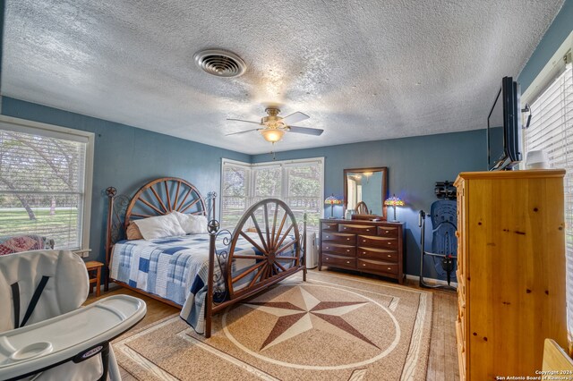 bedroom featuring ceiling fan, wood-type flooring, and a textured ceiling