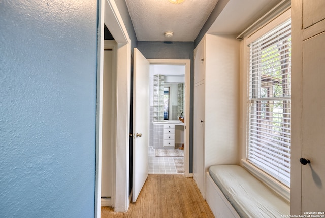 hall featuring a textured ceiling and light hardwood / wood-style flooring