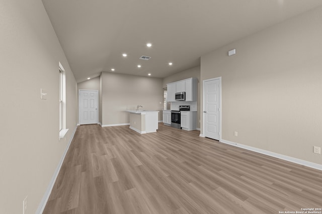 unfurnished living room with sink, lofted ceiling, and light wood-type flooring