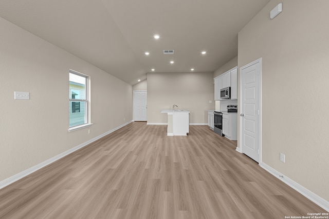 unfurnished living room featuring light wood-type flooring, lofted ceiling, and sink