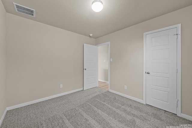 carpeted empty room with a textured ceiling