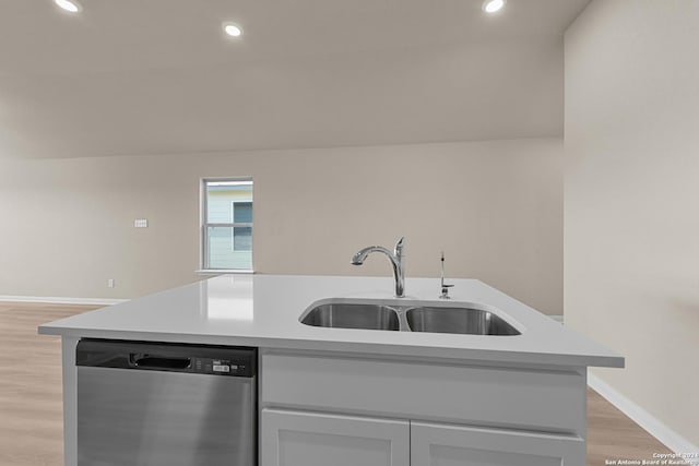 kitchen featuring stainless steel dishwasher, a center island with sink, light wood-type flooring, and sink