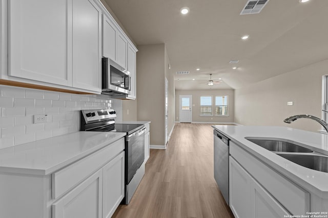 kitchen featuring decorative backsplash, appliances with stainless steel finishes, ceiling fan, sink, and white cabinets