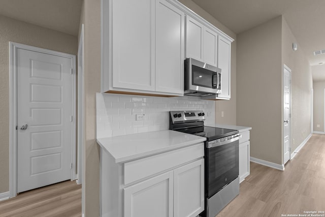 kitchen with decorative backsplash, stainless steel appliances, white cabinetry, and light hardwood / wood-style flooring