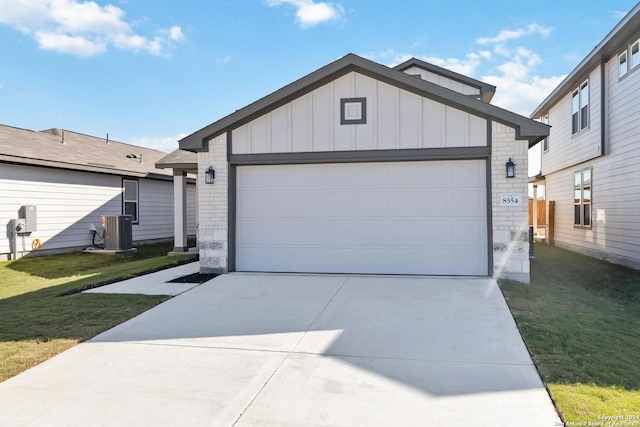 single story home featuring a garage, a front lawn, and central air condition unit