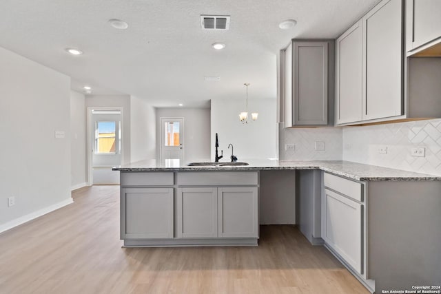 kitchen featuring gray cabinets, sink, and tasteful backsplash