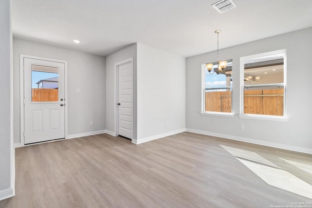 unfurnished dining area with a healthy amount of sunlight, a chandelier, and light wood-type flooring