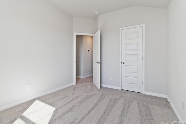 unfurnished bedroom featuring light carpet and lofted ceiling