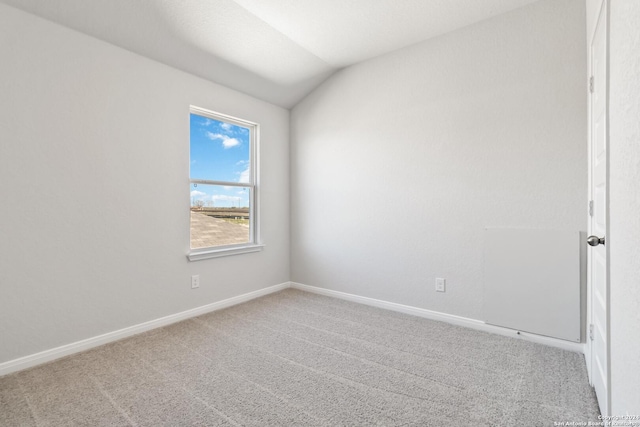 carpeted spare room featuring vaulted ceiling