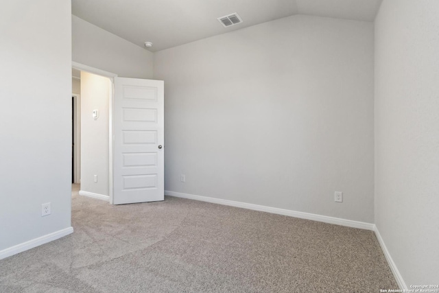 empty room with light colored carpet and vaulted ceiling