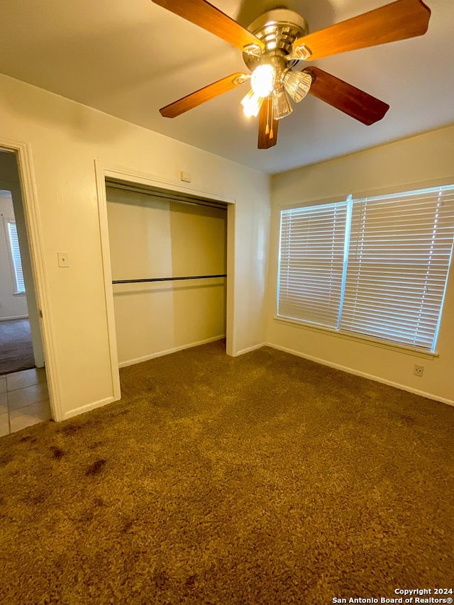 unfurnished bedroom with ceiling fan, a closet, and dark colored carpet