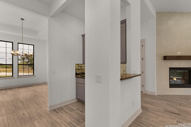 hallway with beamed ceiling, light hardwood / wood-style floors, and an inviting chandelier