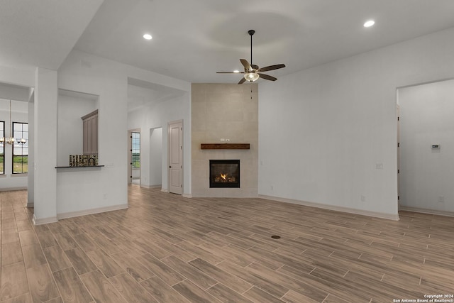 unfurnished living room with ceiling fan, light wood-type flooring, and a tile fireplace