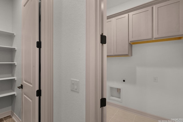 laundry area featuring light tile patterned floors, cabinets, and hookup for an electric dryer