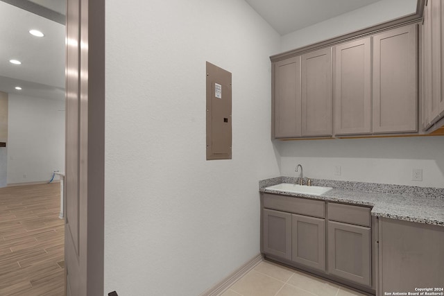 washroom with electric panel, light hardwood / wood-style floors, and sink