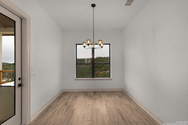 unfurnished dining area featuring light wood-type flooring and an inviting chandelier