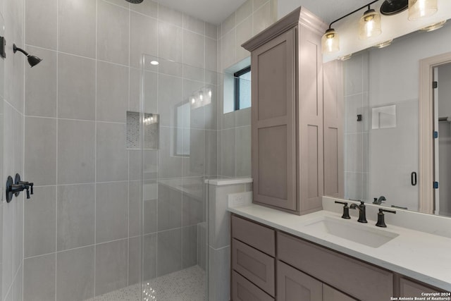 bathroom with tiled shower and vanity