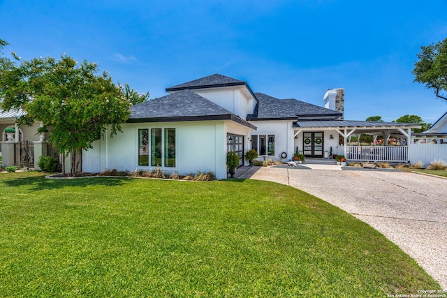 view of front of home featuring driveway, a chimney, a standing seam roof, fence, and a front yard