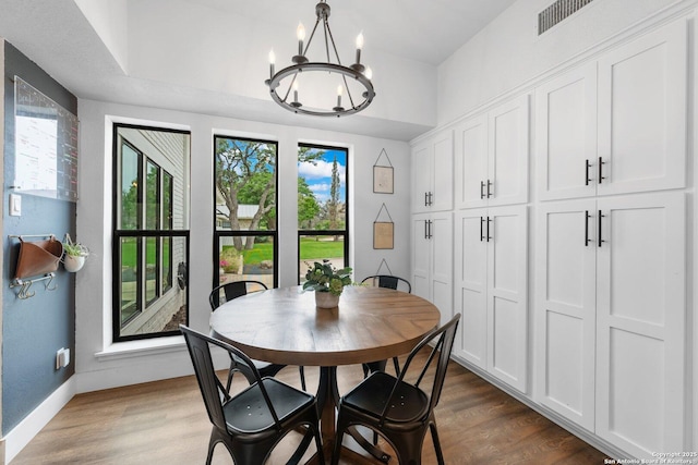 dining area featuring a notable chandelier, visible vents, baseboards, and wood finished floors