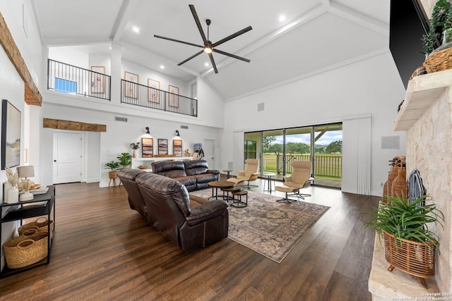 living area with beamed ceiling, a fireplace, wood finished floors, and a ceiling fan