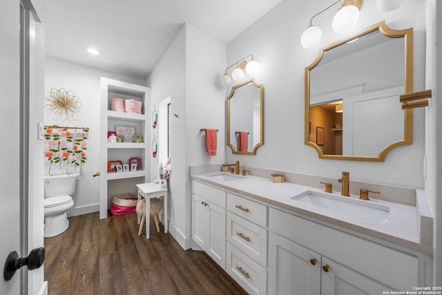 bathroom with double vanity, wood finished floors, a sink, and toilet